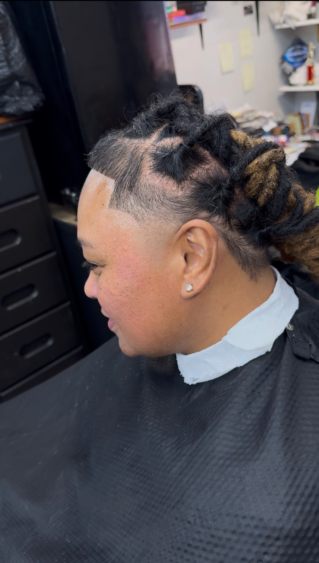 Side profile of mature locs styled up with a lineup and taper, lighter loc ends visible at the back