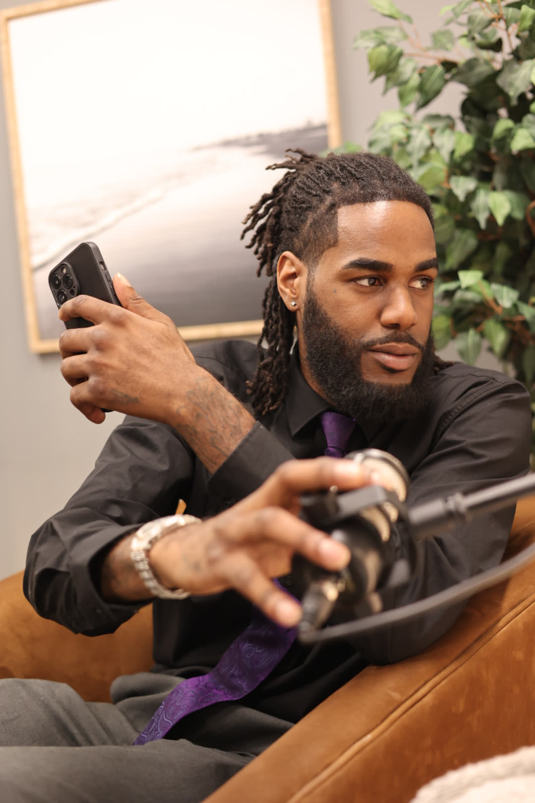 Jayy Klipsz holding a phone in one hand while adjusting a microphone with the other