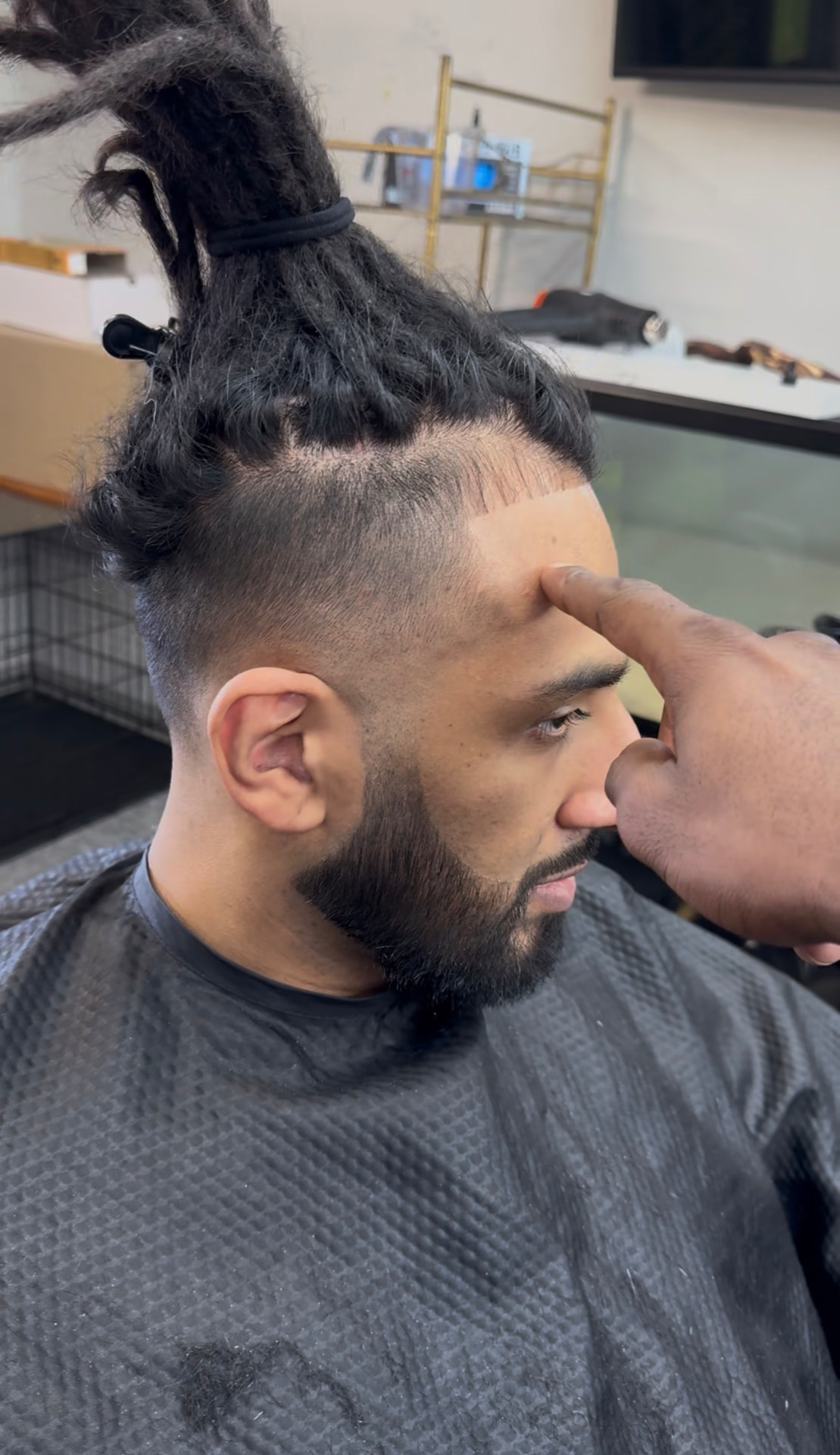Side profile of locs tied up at the crown with a sharp lineup and faded sides