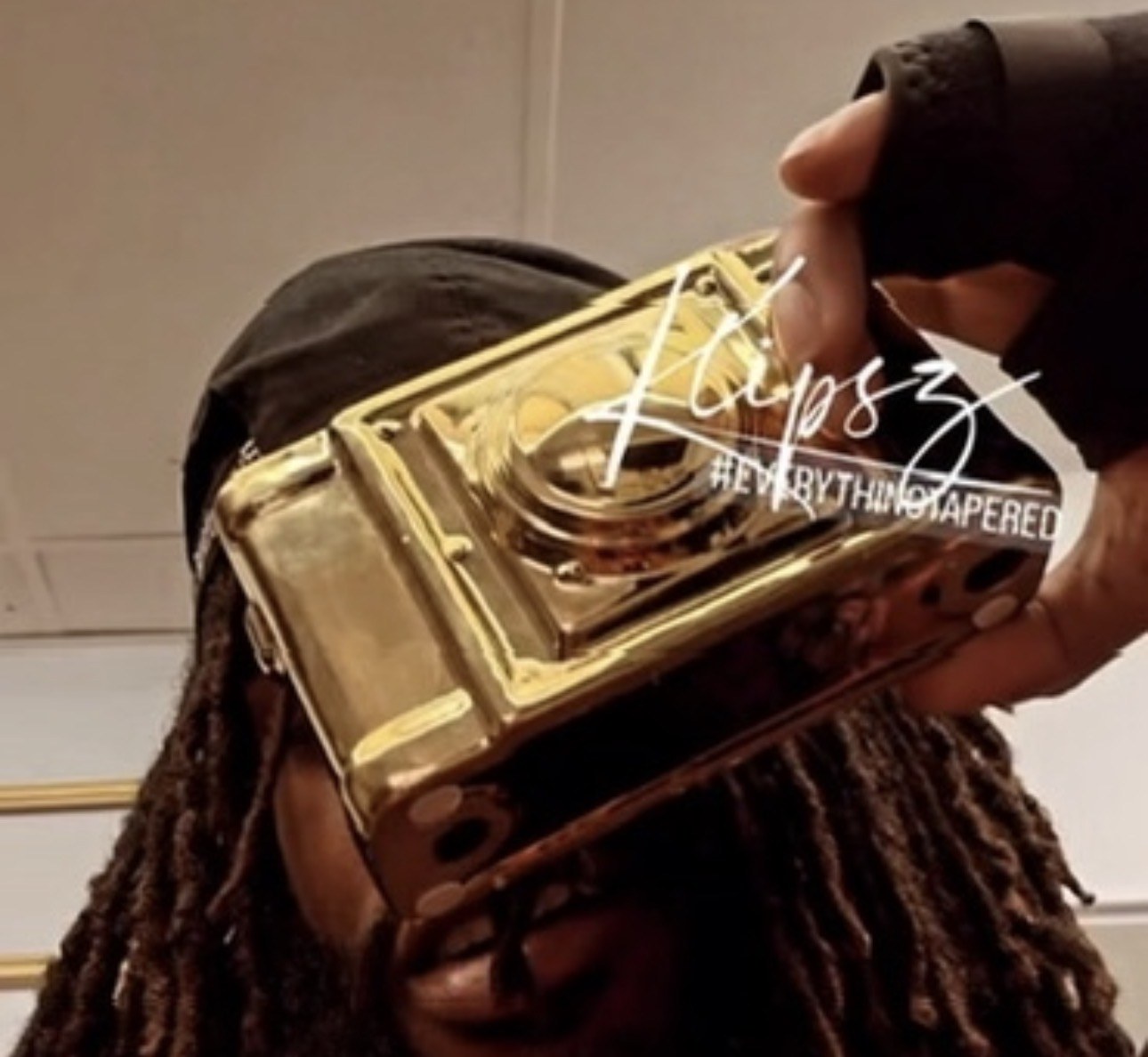 Cubano Jayy holding a gold film camera with the Everything Tapered mark across the frame