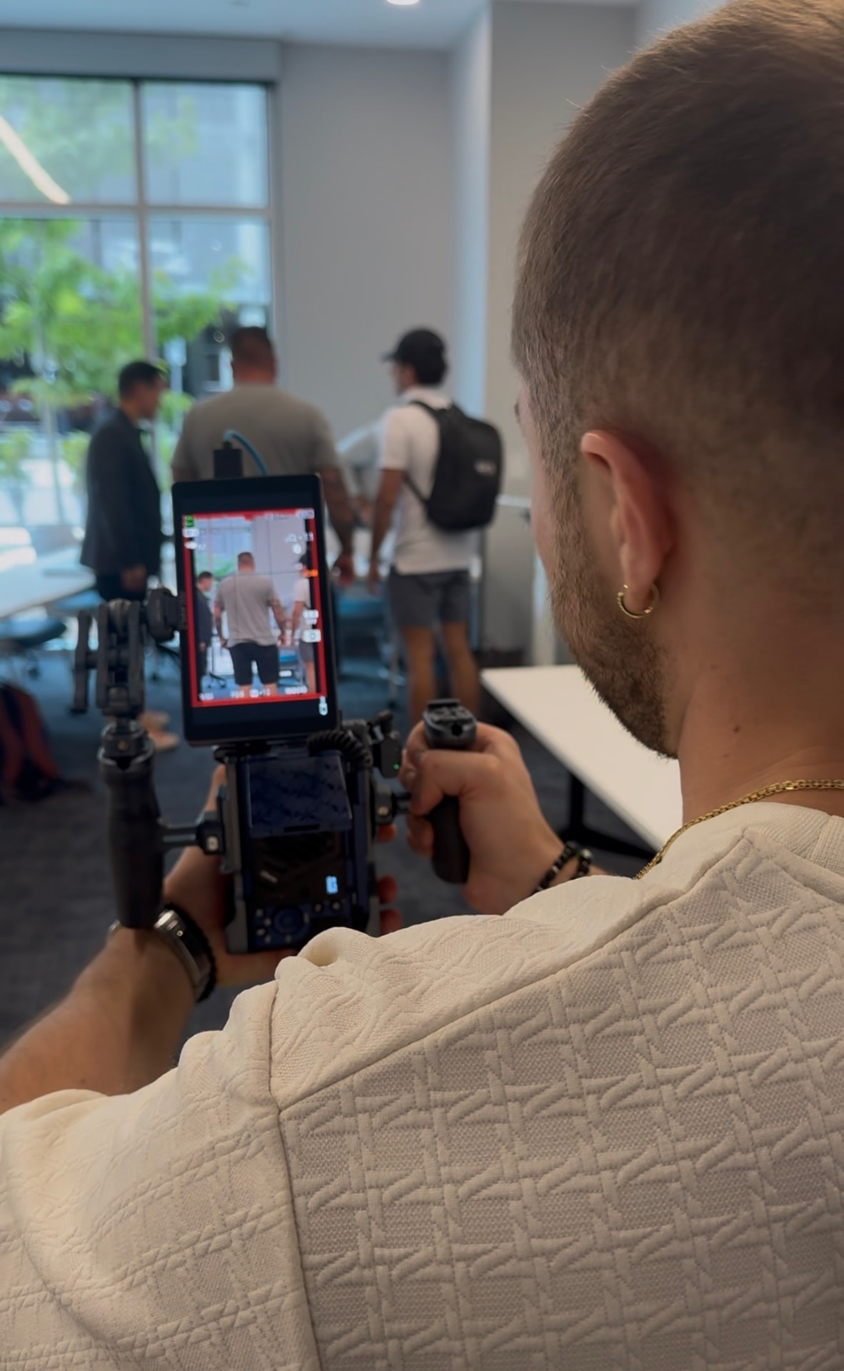 Camera operator framing a shot on a rigged camera with an external monitor during a filmed session